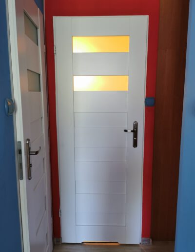 Przykładowa realizacja montażu białych drzwi do łazienki na kolorowych ścianach
