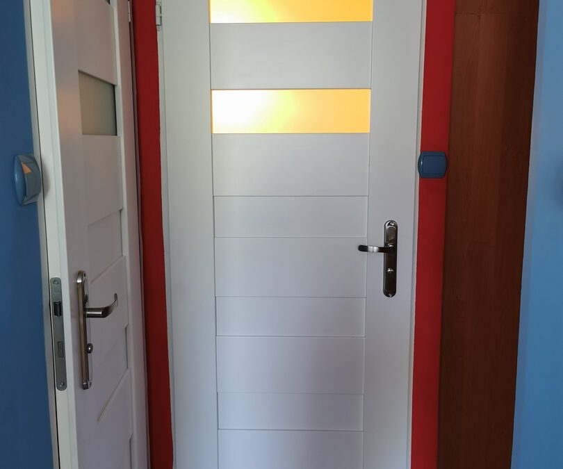Przykładowa realizacja montażu białych drzwi do łazienki na kolorowych ścianach