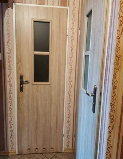 Drewniane wąskie drzwi z otworami wentylacyjnymi do łązienki