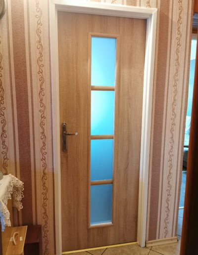Przykładowa realizacja montażu drzwi do pokoju z pionowymi wąskimi matowymi oknami