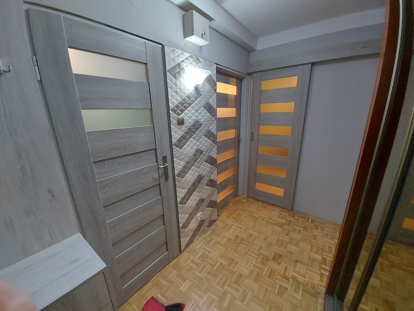 Przykład montażu jasnych drzwi domowych z matowymi oknami w paski